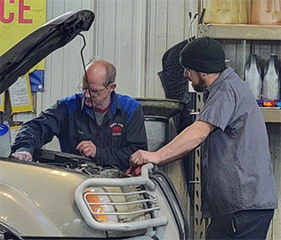Tom's Auto Center - Mechanics working Carry Works on a Car - Tom's Auto Center